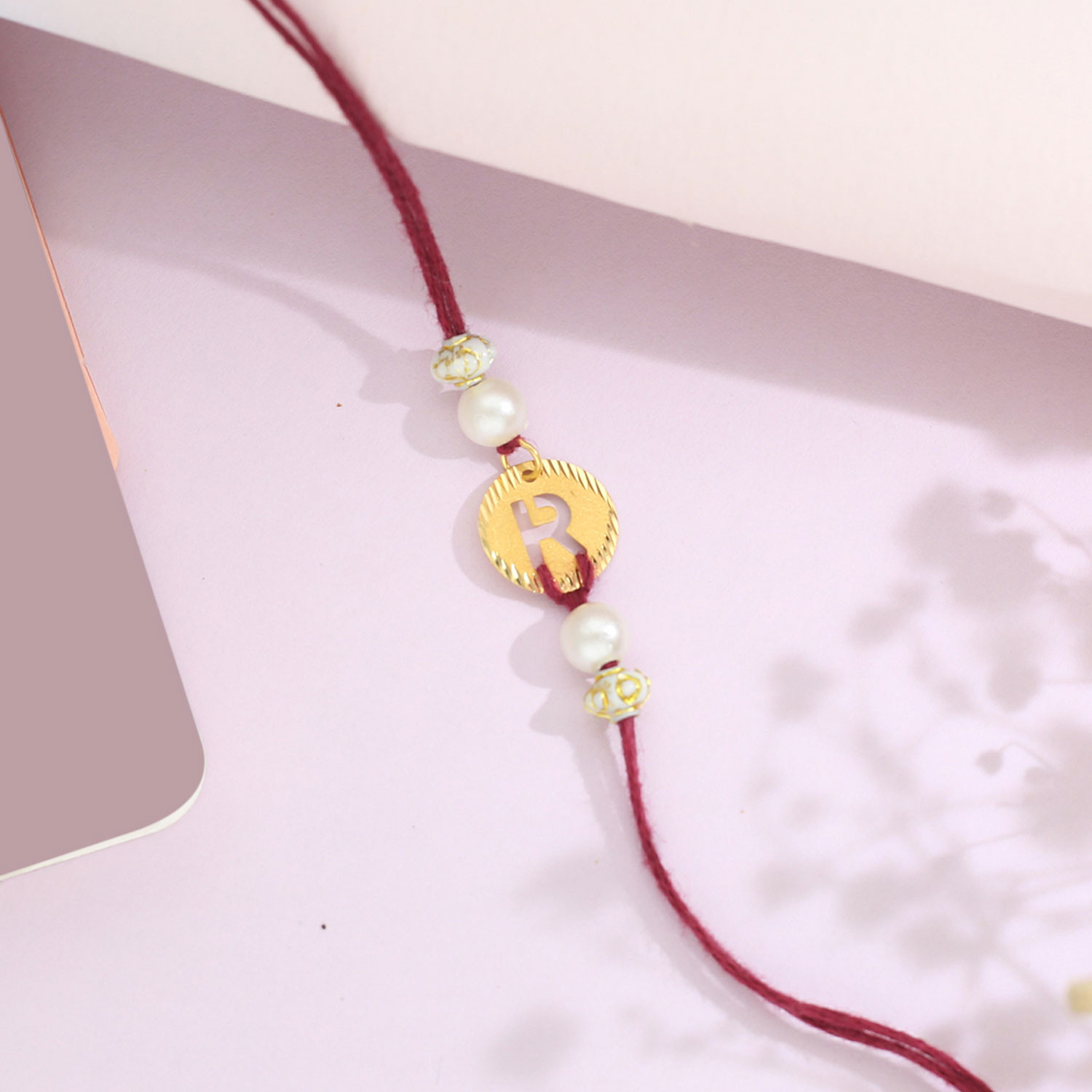 Malabar Gold Circle Motif R Alphabet Two-in-One Rakhi and Pendant